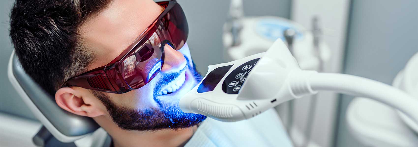 A young man using an advanced tooth whitening system at the dental